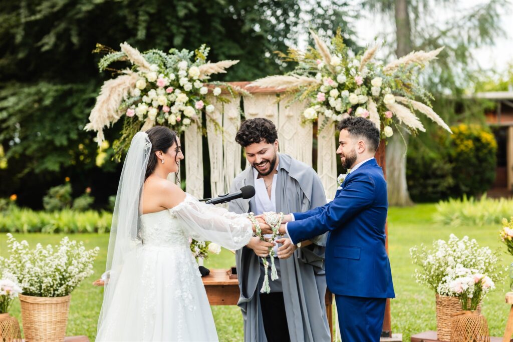 Oficiante de bodas atando las manos de una pareja con una cuerda de handfasting
