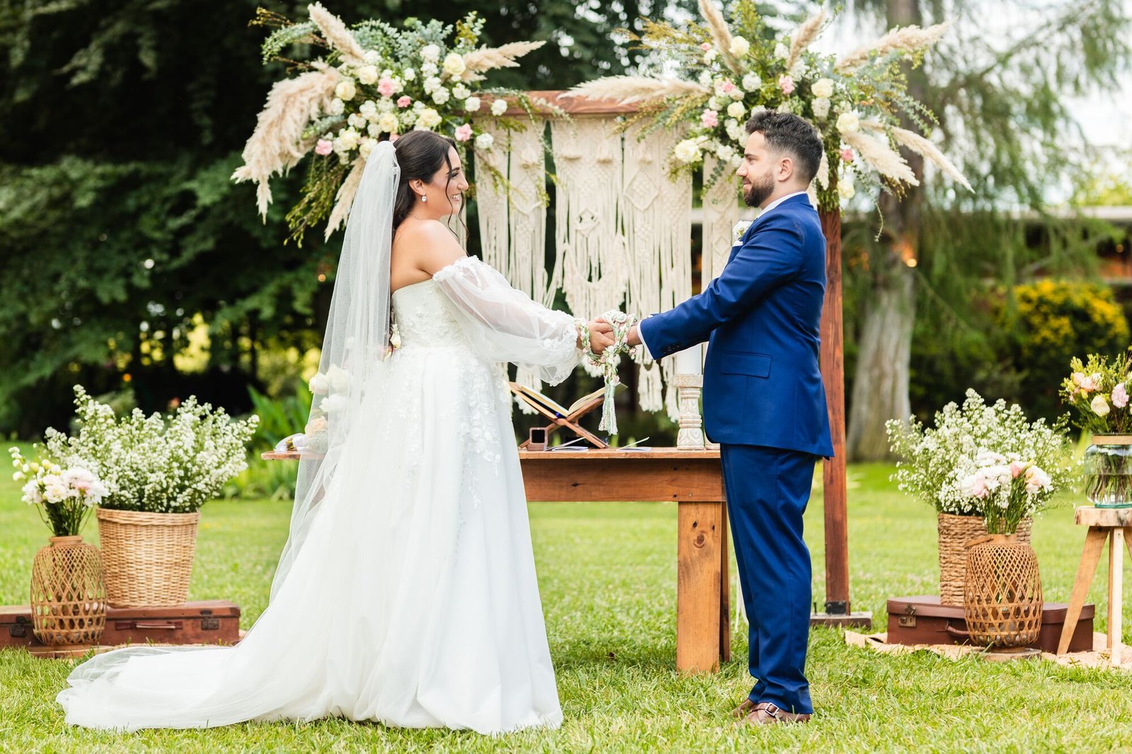 Novios se miran frente al altar de flores al aire libre